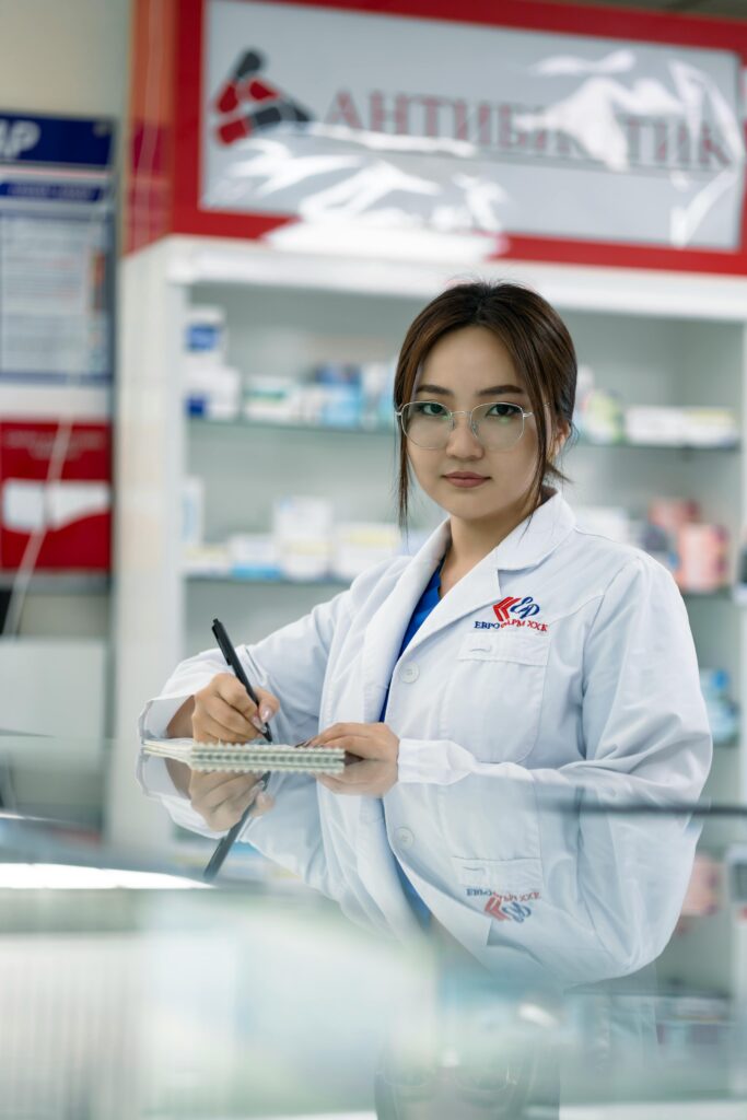 pexels-photo-19471016-19471016 Female pharmacist writing in notepad inside a pharmacy.