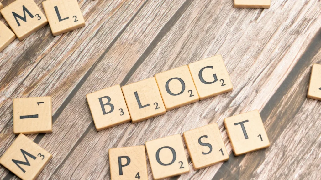 Wooden letter tiles spelling out "BLOG POST" on a rustic wooden background, with scattered letters around the edges.